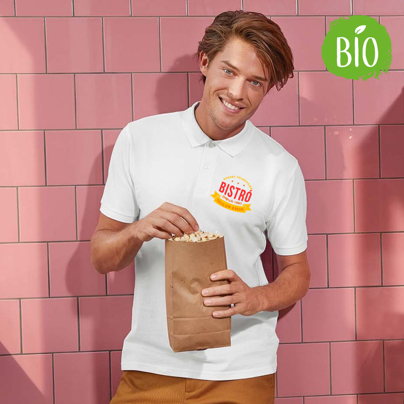 Jeune homme souriant mangeant du pop-corn. Il porte un polo 100 % coton biologique personnalisé en impression quadri