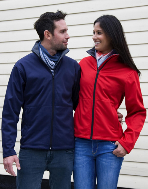 couple se tenant par la hanche portant chacun une veste softshell personnalisable en broderie