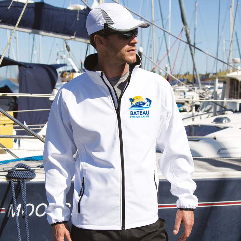 Homme avec veste softshell blanche et casquette blanche debout face au port