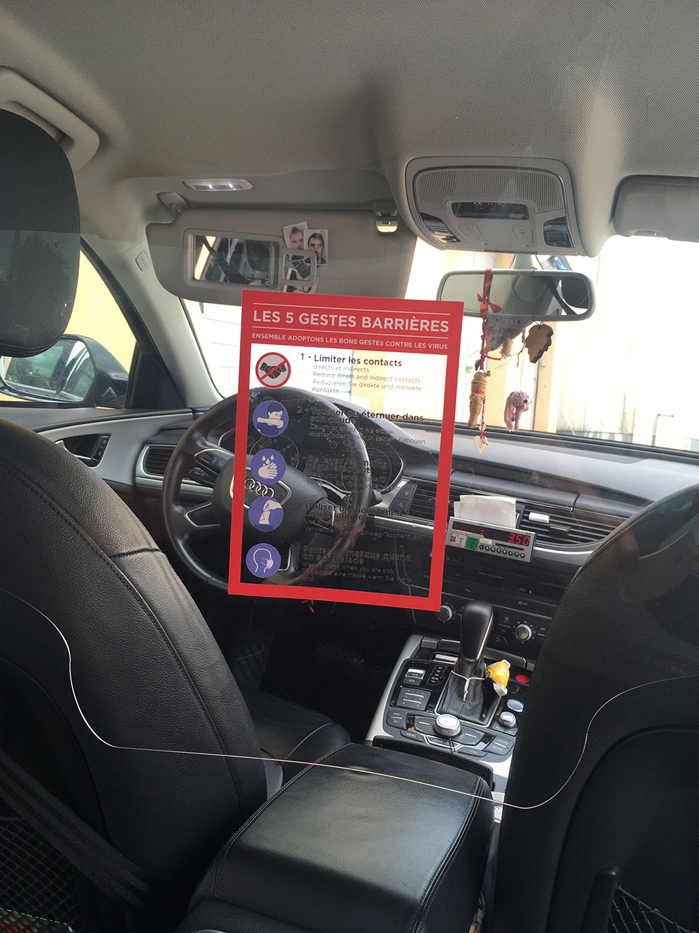 Sticker de rappel des gestes barrières appliqué sur un ecran de séparation chauffeur - passager dans un txi ou vtc